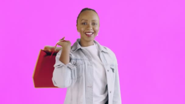 Portrait of african american woman with shopping bags on pink Background in Studio. Happy Woman Holding Shopping Colorful Bags. Jean jacket — Stock Video