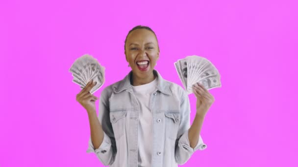 Удовлетворенный счастливый взволнованный африканский американец, показывая деньги и говоря о Боже мой на розовом фоне Жан куртка — стоковое видео