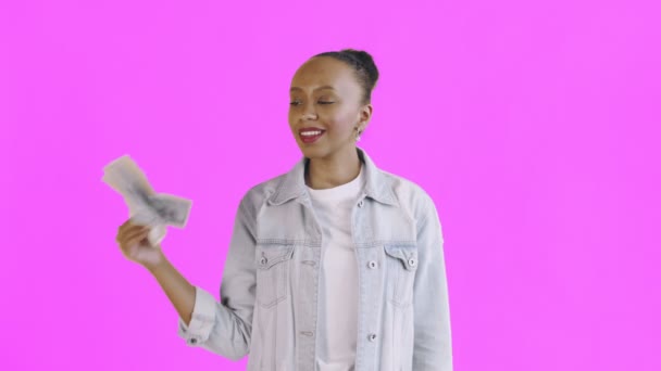 Удовлетворенная африканская американка с деньгами показывает большой палец вверх на розовом фоне Жан куртка — стоковое видео