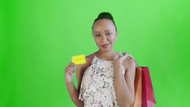 Uma afro-americana com um cartão de crédito e pacotes nas mãos. Tela verde. Vestido branco com flores — Vídeo de Stock