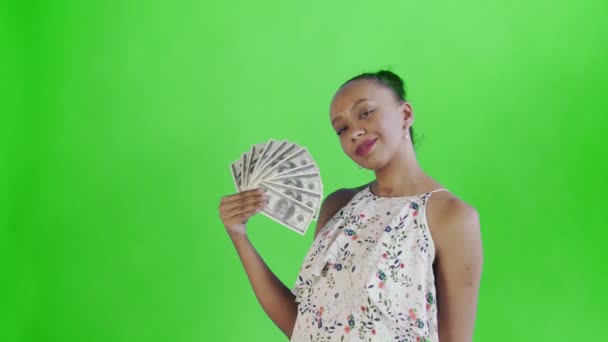 African american woman with money fan on green Background in Studio. White dress with flowers — 图库视频影像