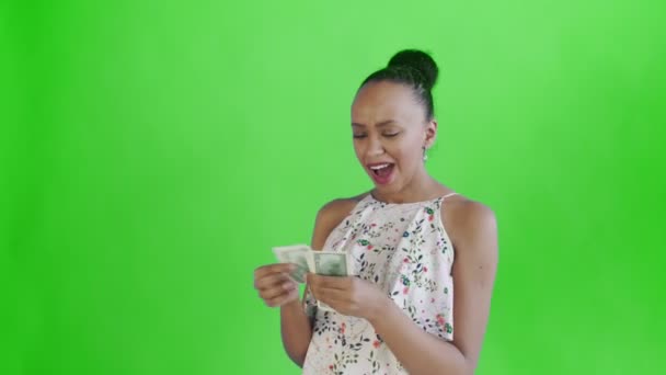 Attractive Afro american woman is counting money against a green background. White dress with flowers — Stockvideo