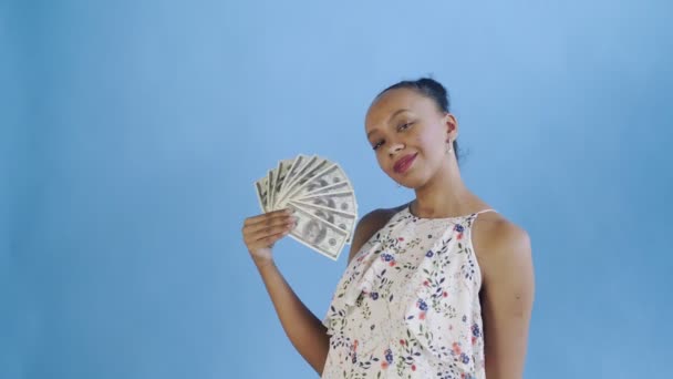 Femme afro-américaine avec ventilateur d'argent sur fond bleu dans Studio. Robe blanche avec des fleurs — Video