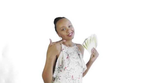Africká Američanka tančí s penězi a ukazuje palec nahoru na bílém pozadí v ateliéru. Bílé šaty s květinami — Stock video