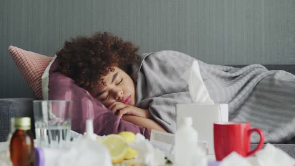 Ill young african american girl is sleeping relaxing during disease lying on couch in apartment under warm plaid. — Stock Video