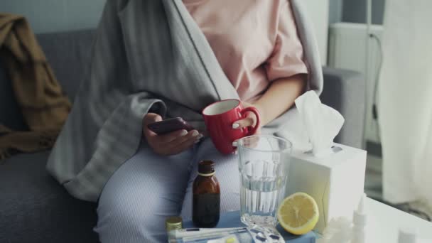 Close up of sick Young african american girl using phone and drinking a hot tea at home — Stock Video