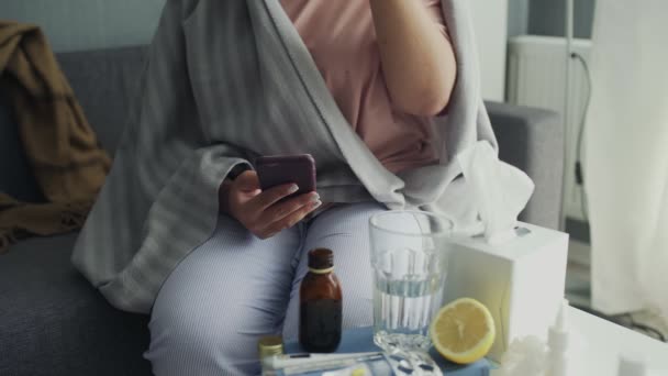 Zbliżenie w górę w górę w chory młody afrykański amerykański dziewczyna za pomocą telefon i picie a Gorąca herbata w dom — Wideo stockowe