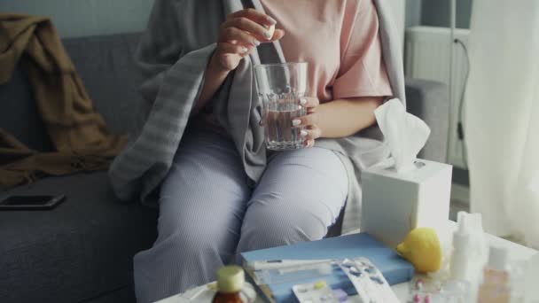 Brausetablette in Großaufnahme in einem Glas Wasser. Krank afrikanisch amerikanisch mädchen sitzt auf sofa — Stockvideo