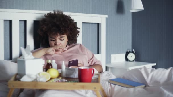 Enfermo joven afroamericano chica usando el teléfono en la cama en casa — Vídeos de Stock