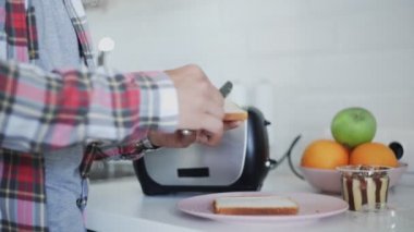 Adam tostun üstüne çikolata sürerken kahvaltı hazırlıyor..