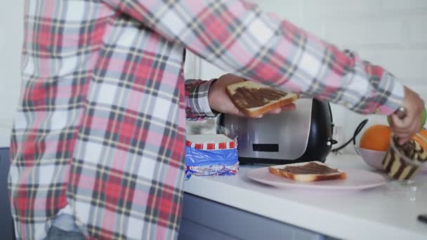 Muž dělá snídani, když rozmaže čokoládovou pomazánku na toast. — Stock video