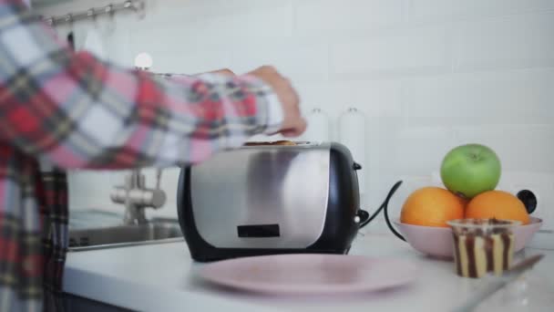 Ein Mann legt Brot in einen Toaster. Das Brot wird gebraten. Das Frühstücksbuffet wird zubereitet. Elektrogeräte in der Küche — Stockvideo