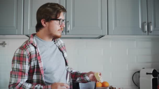 Joven comiendo tostadas con mermelada de fresa y bebiendo un zumo de naranja — Vídeo de stock
