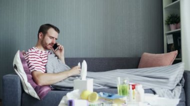 Hasta genç adam evde telefonla konuşuyor.