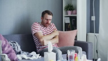 Gri ekoseli genç adam donuyor evde üşüyor, hasta hasta adam grip gribi belirtileri gösteriyor.