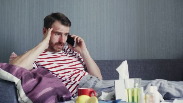 Больной молодой человек разговаривает по телефону дома — стоковое видео