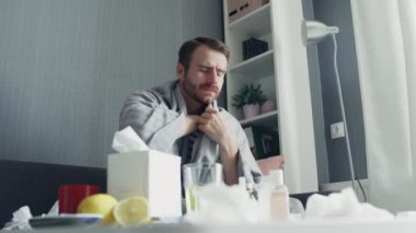 Evdeki kanepede oturan grip hastası adam. Soğuk termometreyle ateşini ölçen hasta bir genç.