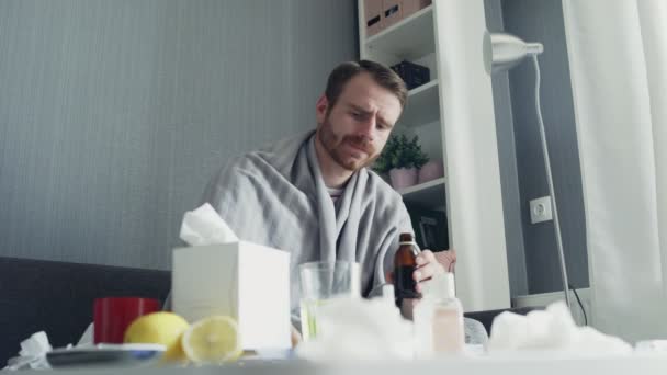 Sick man pouring medication or antipyretic syrup to spoon and drinking it — Stock Video