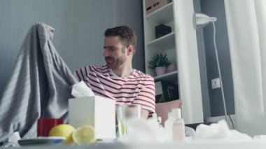 Gri ekoseli genç adam donuyor evde üşüyor, hasta hasta adam grip gribi belirtileri gösteriyor.