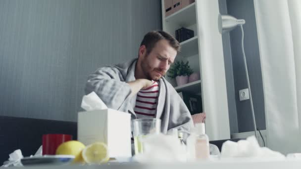 Nemocný muž s chřipkou sedí doma na gauči. Nemocný mladý muž se studenou kontrolní teplotou s teploměrem — Stock video