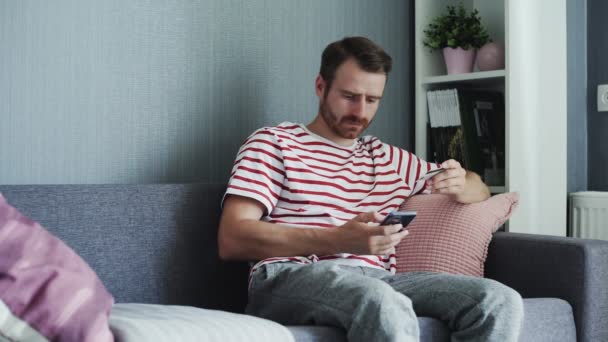 Homem usando telefone inteligente para compras on-line com cartão de crédito — Vídeo de Stock