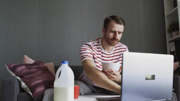 Freelancer desayunando y usando un portátil para trabajar — Vídeos de Stock