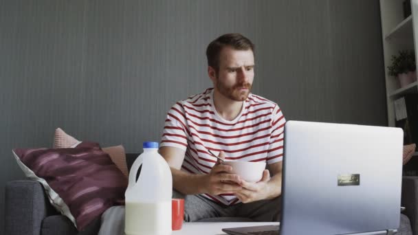 Geschokt man ontbijten en het gebruik van een laptop om verschrikkelijk nieuws te lezen — Stockvideo