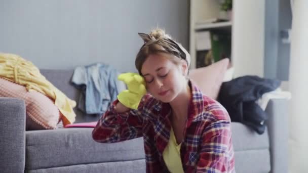 Portret van een vermoeide vrouw die de vloer van de woonkamer schoonmaakt — Stockvideo