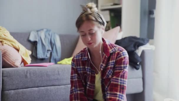 Portrait of a woman with headphones is cleaning the floor of the living room — Stock Video