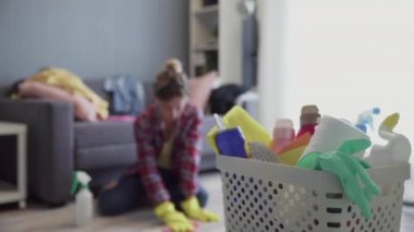 Sepet dolusu sünger ve arka planda bulanık bir kadın olan ev kimyasalları.