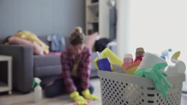 스펀지와 가정용 화학 물질로 가득 찬 욕조 뒤에 불분명 한 배경의 여자 — 비디오