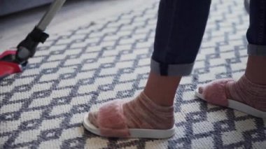 Halıyı temizlemek için elektrikli süpürge kullanan genç bir kadın.
