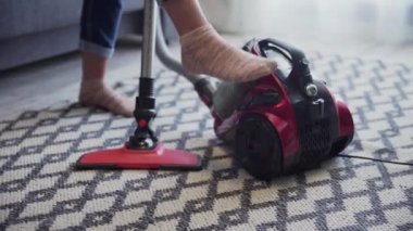 Kadın elektrik süpürgesini açtı ve halıyı temizlemeye başladı.