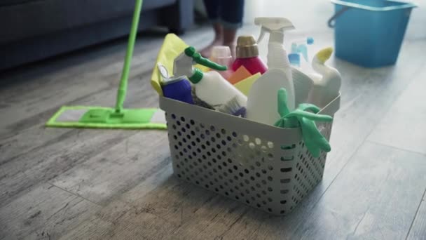 Cesta llena de esponjas y productos químicos para el hogar con la mujer limpiando el suelo con una fregona — Vídeo de stock