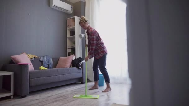 Mooie jonge vrouw schoonmaken vloer met dweil. — Stockvideo