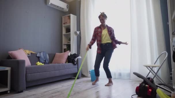 Feliz joven mujer linda ama de casa está lavando piso con fregona y bailando en casa — Vídeos de Stock