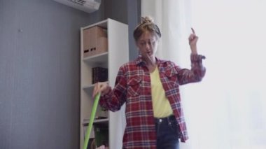 Kadın paspasla yerleri yıkıyor ve evde dans ediyor.