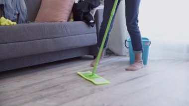 Kadın paspasla yerleri yıkıyor ve evde dans ediyor.