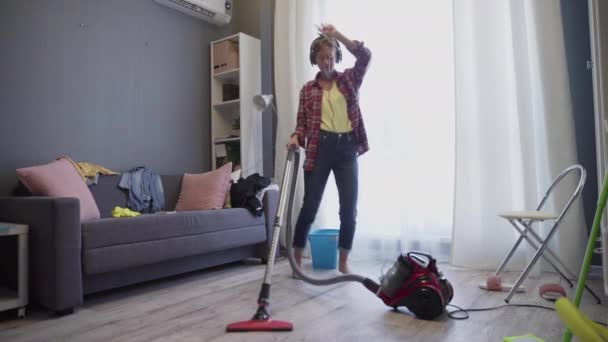 Jonge vrouw met behulp van een stofzuiger op de vloer — Stockvideo