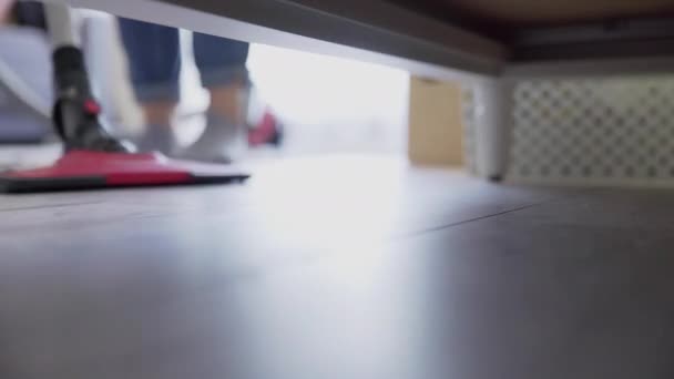 Жінка використовує пилосос для прибирання підлоги під ліжком — стокове відео