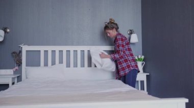 Yatak odasındaki yatağı genç kadın yapıyor.