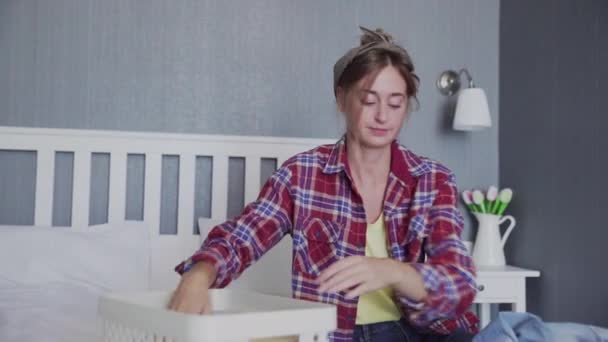 Mooie jonge vrouw sorteert kleding op het bed — Stockvideo
