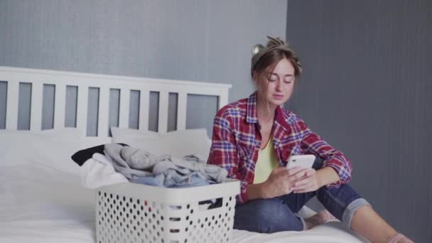 Beautiful young woman is resting on the sofa after doing laundry — Stock Video