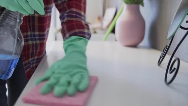 Молодая женщина с помощью розовой губки удаляет пыль со стола — стоковое видео