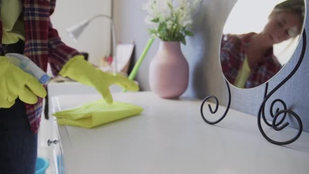 Jovem mulher usando um pano amarelo para remover o pó da mesa — Vídeo de Stock