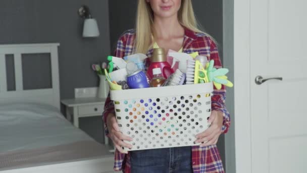 Mujer irreconocible con la cesta llena de esponjas y productos químicos del hogar mirar a la cámara — Vídeos de Stock