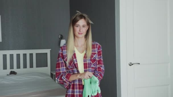 Ung hemmafru tar på sig gröna handskar — Stockvideo