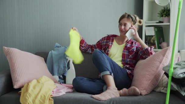 Красивая молодая женщина отдыхает на диване после уборки и разговора по телефону — стоковое видео