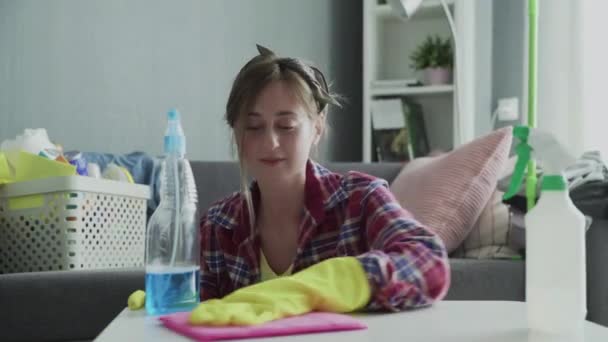 Mujer joven usando una esponja rosa para quitar el polvo de la mesa — Vídeo de stock