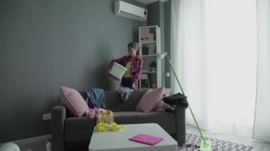 Kadın sepetten dağınık eşyaları topluyor.
